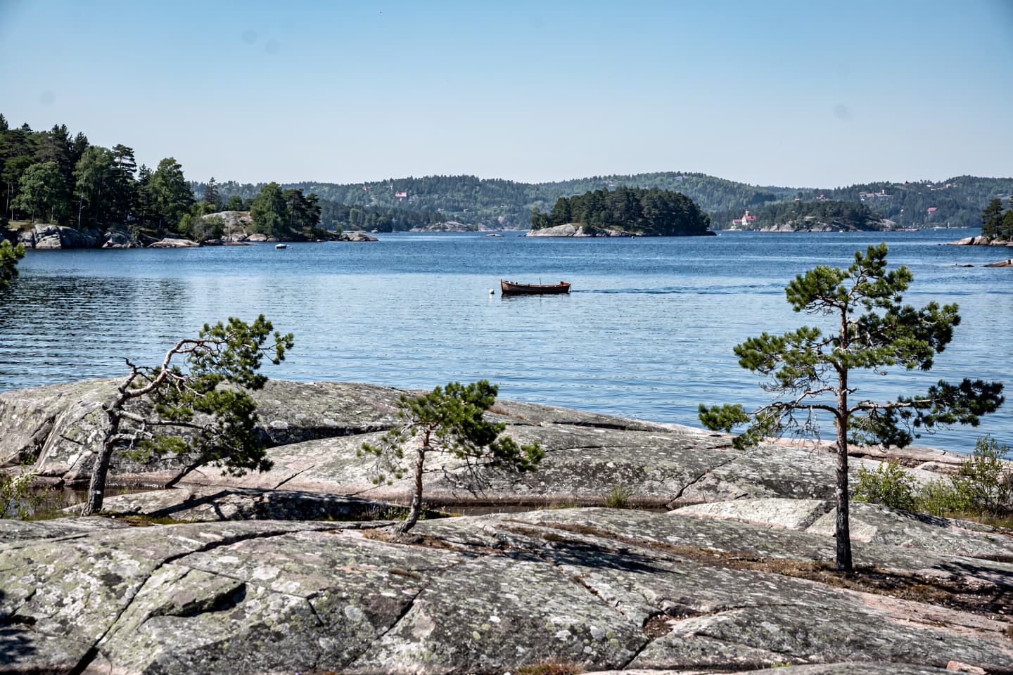 AI-generated: Klippöar med tallar och en liten träbåt i Stockholms skärgård