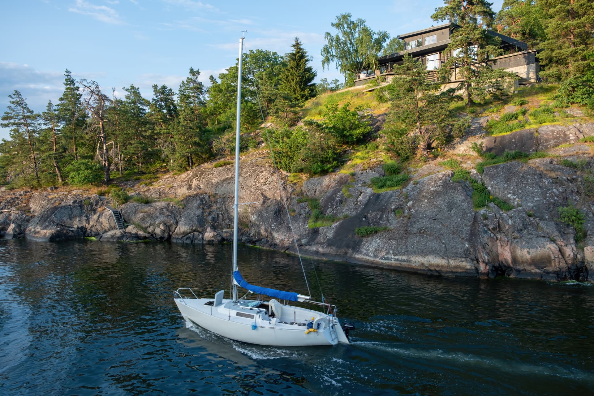 Villa vid vattnet med förtöjd segelbåt i Stockholms skärgård